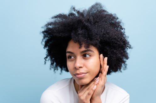 Close-up of a happy black woman looking to the side against a blue background