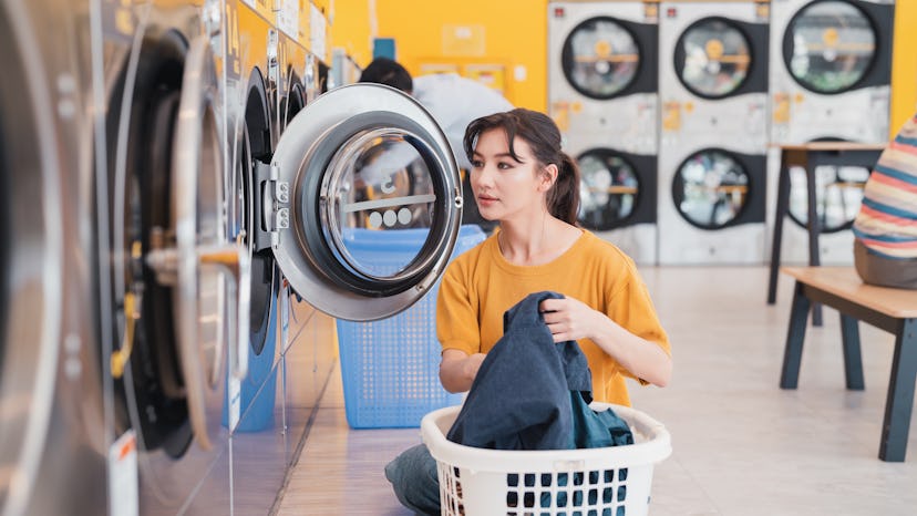 woman using a washing machine at the laundromat.Self-service adults use state-of-the-art washing mac...