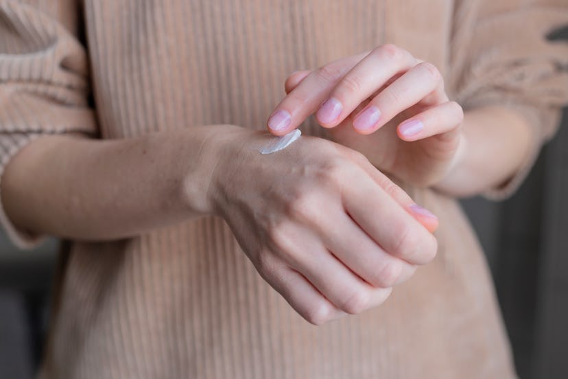 Woman uses hand cream. Self care concept.