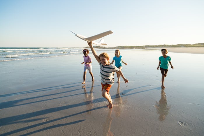 Group of children running along a deserted beach with a model plane, in a story about tips for trave...
