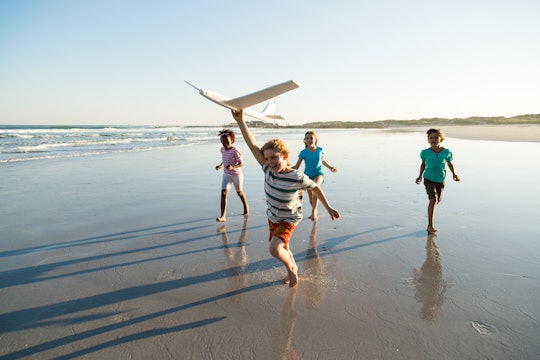Group of children running along a deserted beach with a model plane, in a story about tips for trave...