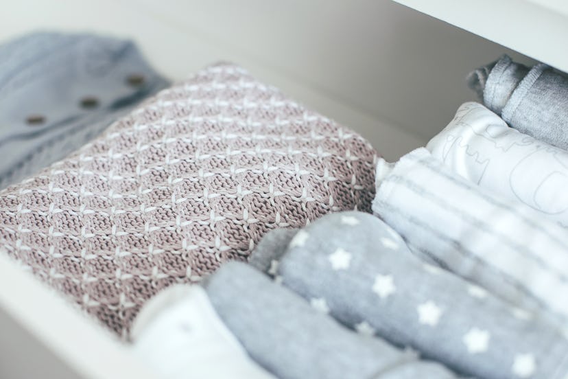 Baby or newborn things of white, blue and grey colors are in the drawer. Lady fly system, kondo, kon...