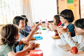 School Students eating lunch in School Cafeteria; Pandemic food aid programs will end in 32 states o...