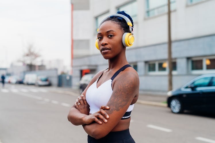 Italy, Milan, Portrait of woman in sports bra and headphones in city