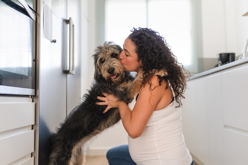 pregnant person cuddling their dog. can dogs sense labor?