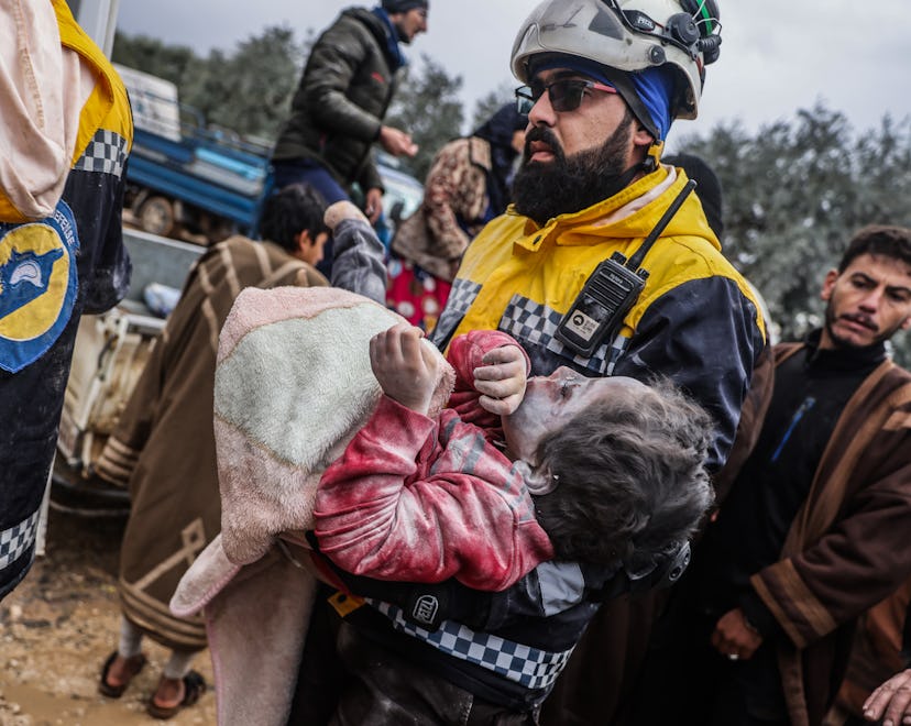 Members of the Syrian White Helmets carry a body of a girl from a destroyed building following a mag...