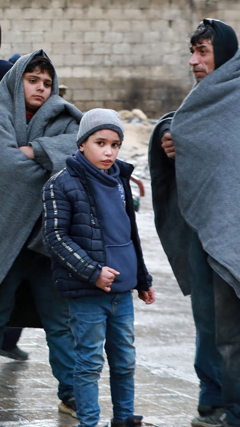 A Syrian man and children gather outside on a street following a deadly earthquake on February 6, 20...