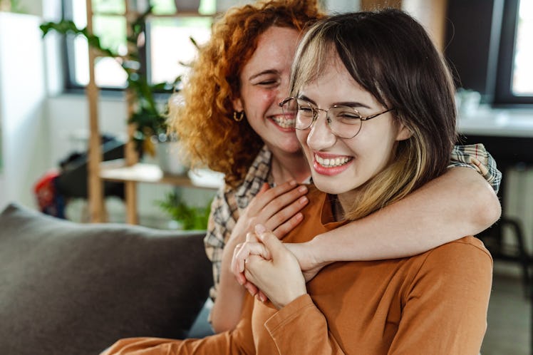 Two young women laughing as they discuss how their zodiac sign acts when they have a crush.