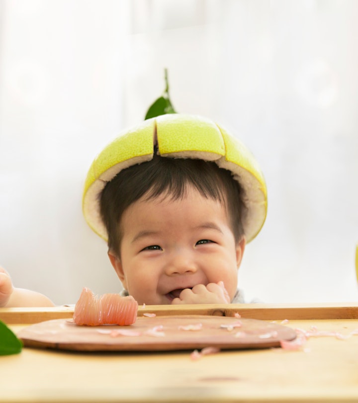 Toddler eating fruits with a pomelo hat, in a story about fruit baby names.