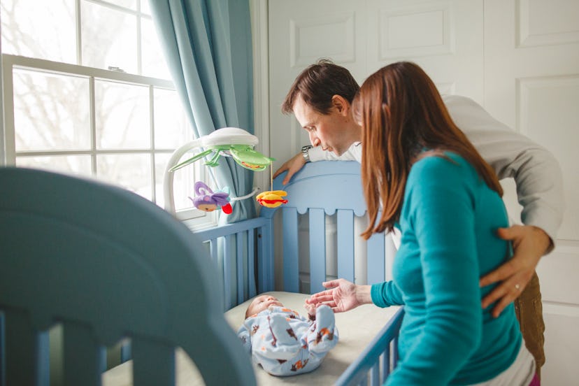 a couple with their baby in a crib, how to survive sleep regressions