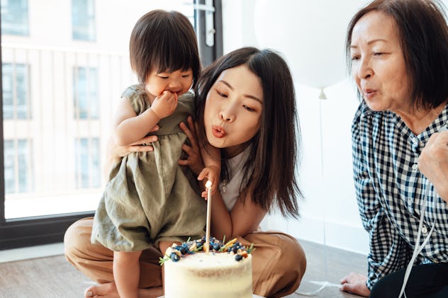 Mother and grandmother celebrating her baby’s birthday at home with a birthday cake. They'll post pi...
