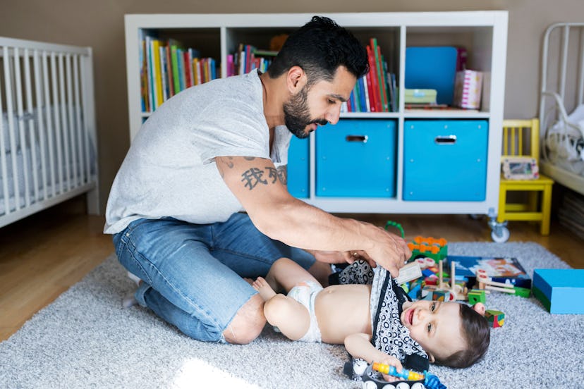 A dad wondering why do some toddlers love to be naked as he wrestles his little one into clothes.