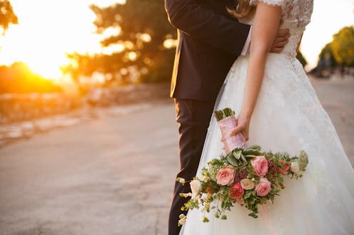 Bride and groom hugging with wedding bouquet in her hand