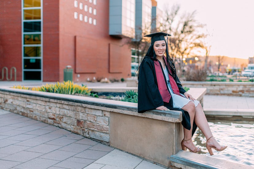 A young hispanic woman wearing a cap and gown. She is a first generation university or high school g...