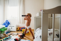 A toddler in a diaper uses a play telescope, in a story answering the question why do some toddlers ...