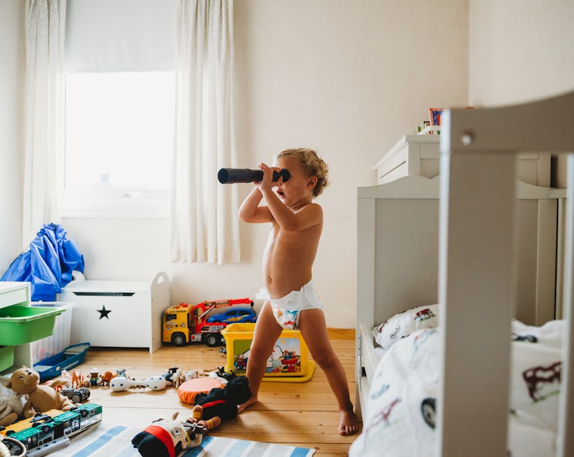 A toddler in a diaper uses a play telescope, in a story answering the question why do some toddlers ...