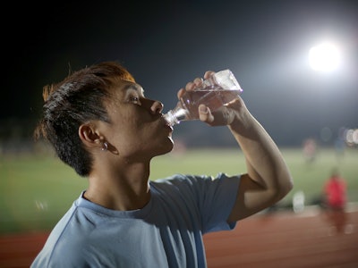 An Asian man is drinking water after fitness training at night