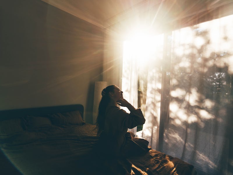 Young woman in bathrobe who has just woken up enjoys the rays of the morning sun.