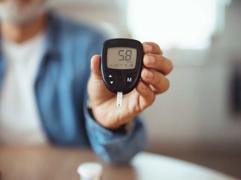 Diabetic checking blood sugar levels. Man checking blood sugar level by glucometer and test stripe a...