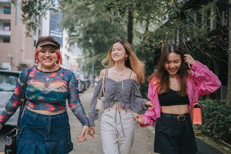 three friends smile and walk down the street together as they consider how they'll be affected by Ap...