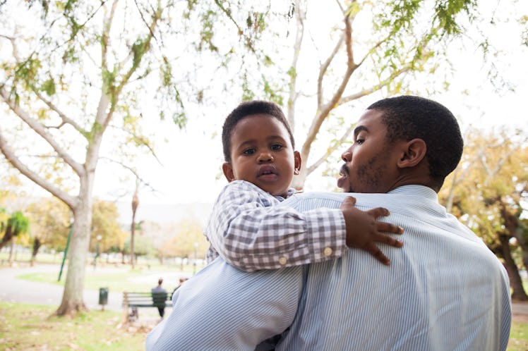 African male holding his baby boy in his arms, baby boy is looking at the camera.