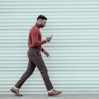 Portrait of African-American young businessman using smartphone while walking