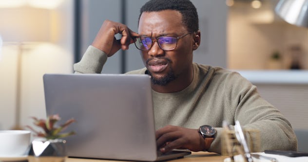 Confused man on a laptop in a list of April Fools' pranks to play on your husband