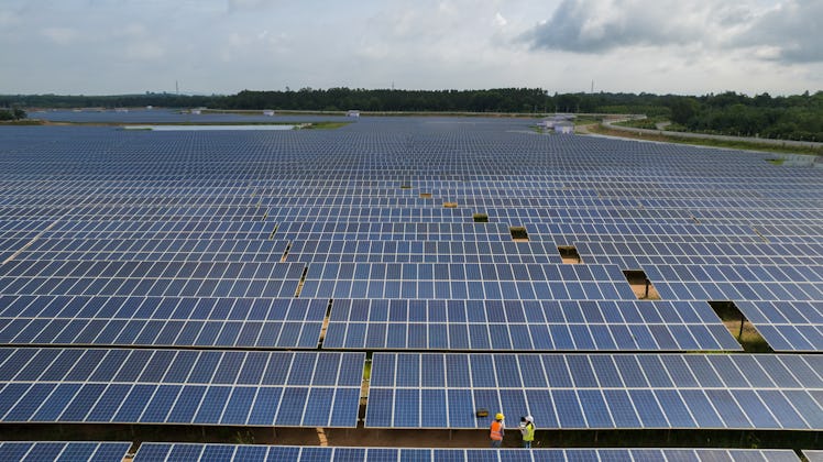 Aerial view of two engineer working in the solar power station farm in Thailand.