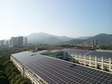 a rooftop covered in solar panels with a cit center and large hills in the distance