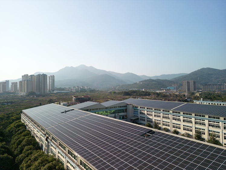 a rooftop covered in solar panels with a cit center and large hills in the distance