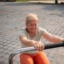 Active senior woman is exercising on a machine in an outdoor gym.