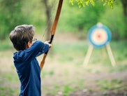 Teenage boy shooting bow outdoors on spring day.
Nikon D850