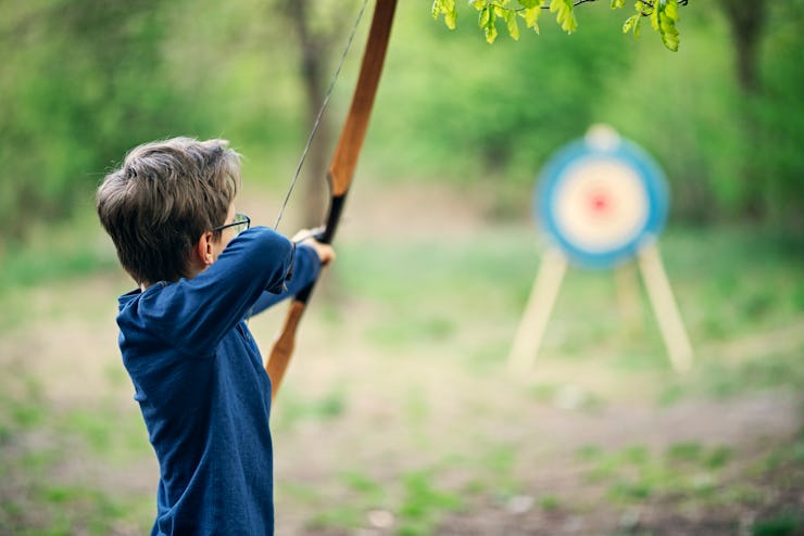 Teenage boy shooting bow outdoors on spring day.
Nikon D850