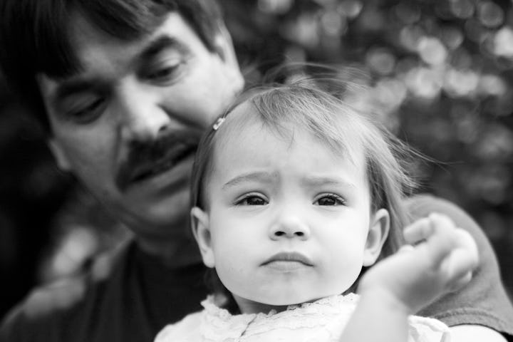 A black and white vintage photo of a dad with a thick mustache and his daughter.