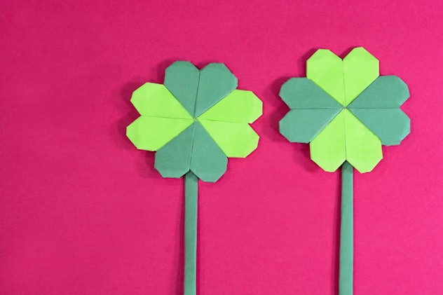 Green Origami clover flowers on a pink background, hide paper or felt shamrocks on st. patrick's day...
