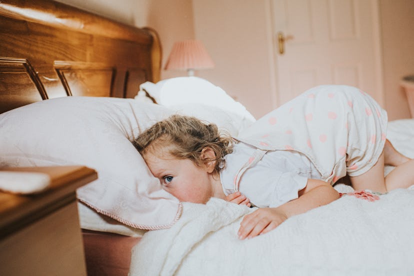 Little girl, in a dated room, playfully burying her head into a pillow. is melatonin safe for kids?