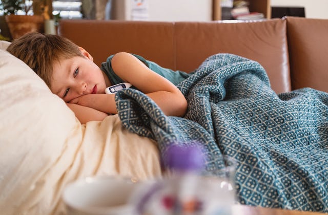Sick little boy lying in bed having a flu