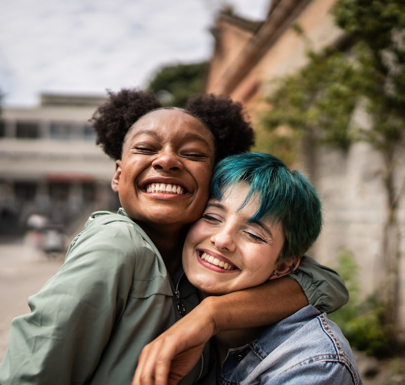 Two friends hugging and smiling, representing the 11th house in astrology, which determines how frie...