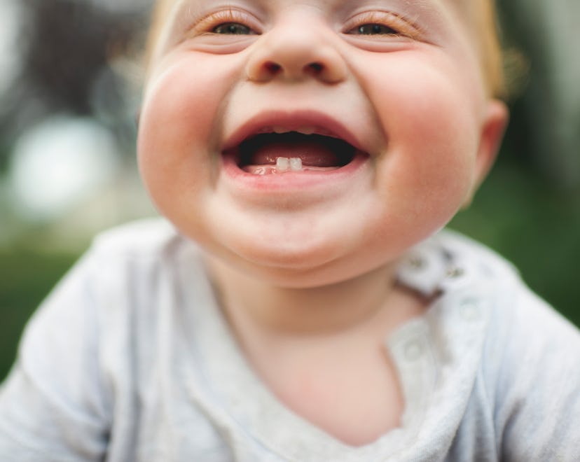 A baby smiles showing off their bottom teeth, in a story about baby milestone Instagram captions.
