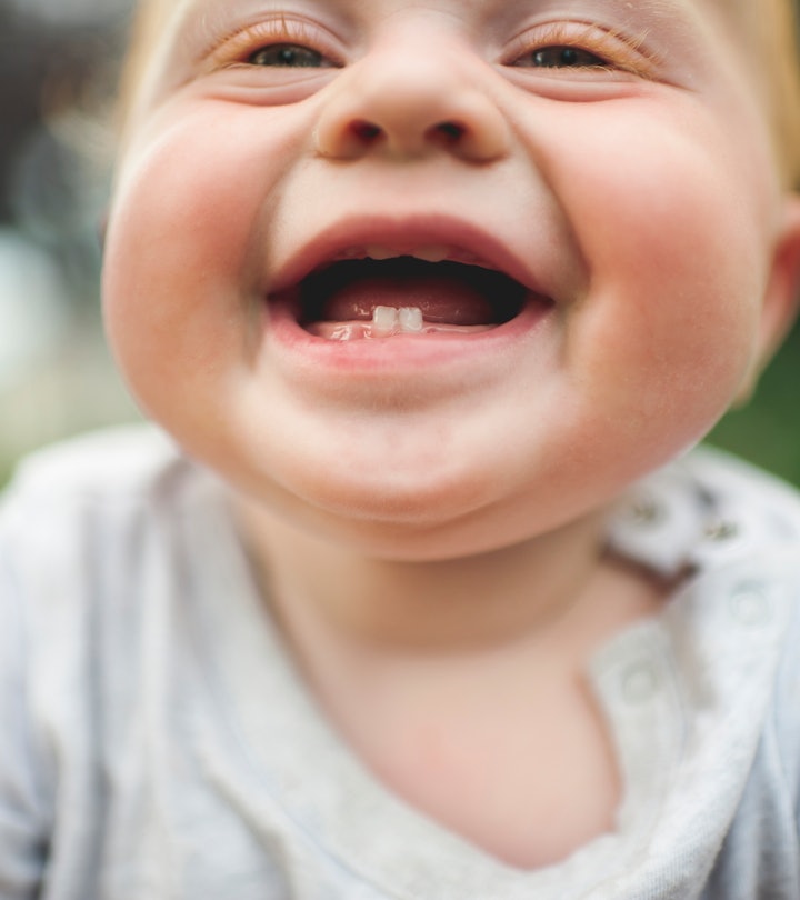 A baby smiles showing off their bottom teeth, in a story about baby milestone Instagram captions.