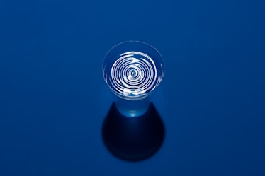 Ripples on Water in a Cup on Blue Background High Angle View.