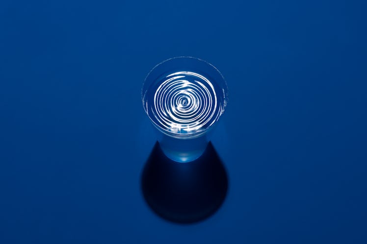Ripples on Water in a Cup on Blue Background High Angle View.