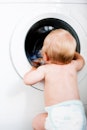 一个婴儿看着洗衣机，在某个时刻，里面会有一块尿布。
