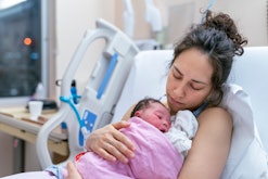 A mother is snuggling her newborn, in an article about postpartum cramps