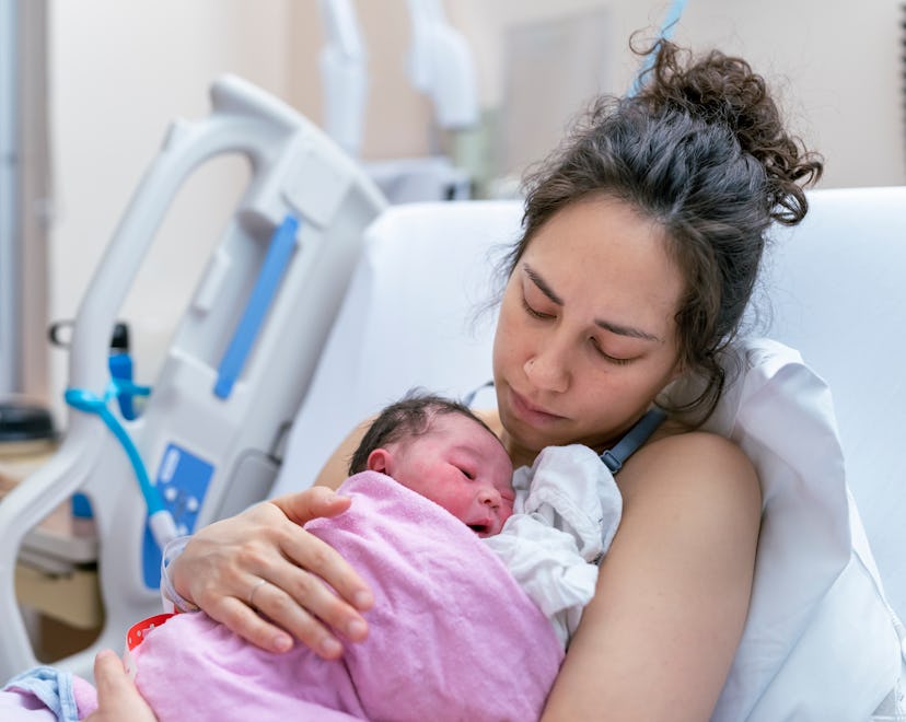 A mother is snuggling her newborn, in an article about postpartum cramps
