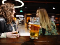 Shot of two young women enjoying a beer together in a nightclub. Close up of unrecognizable couple t...