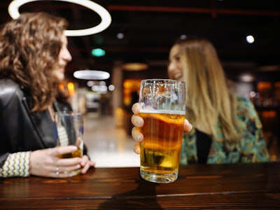 Shot of two young women enjoying a beer together in a nightclub. Close up of unrecognizable couple t...