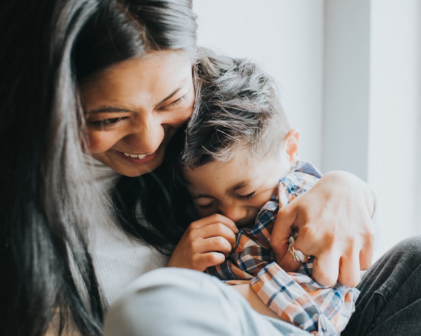 A happy woman cuddles a young giggling boy telling april fools' jokes