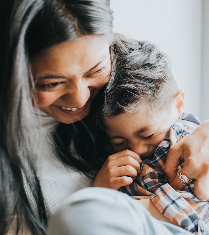 A happy woman cuddles a young giggling boy telling april fools' jokes 