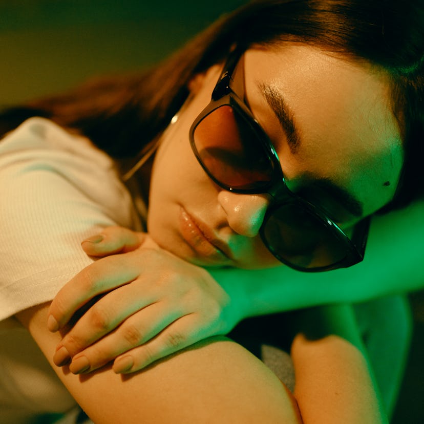 young woman wearing shades poses for a low-lit portrait as she considers how the April 2023 hybrid s...